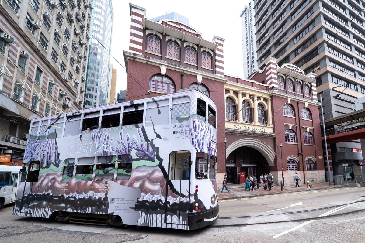 The Tram0 tram, wrapped in grey and purple branching graphics, outside Western Market.