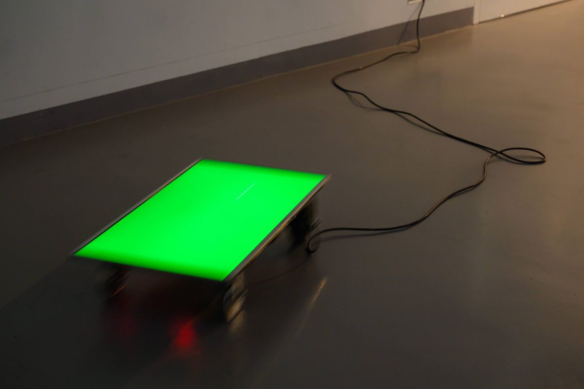 A single trolley glowing green, its cable trailing across the floor.