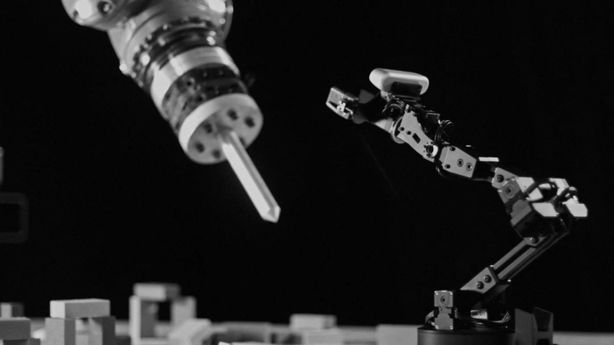 Close-up of the industrial arm’s tool beside a small robot arm.